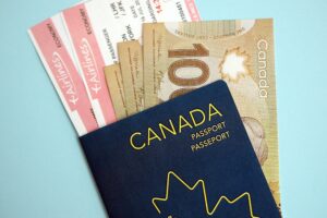 Canadian passport with money and airline tickets on blue background close up